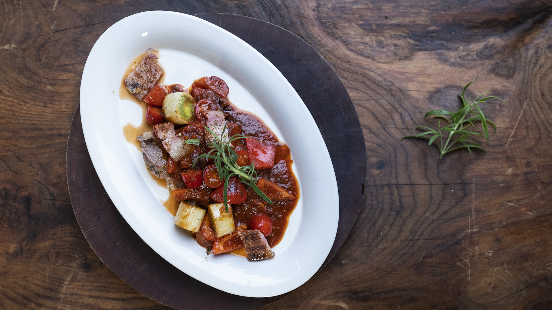 Skinkeschnitzel med bacon og grøntsager i tomatsauce