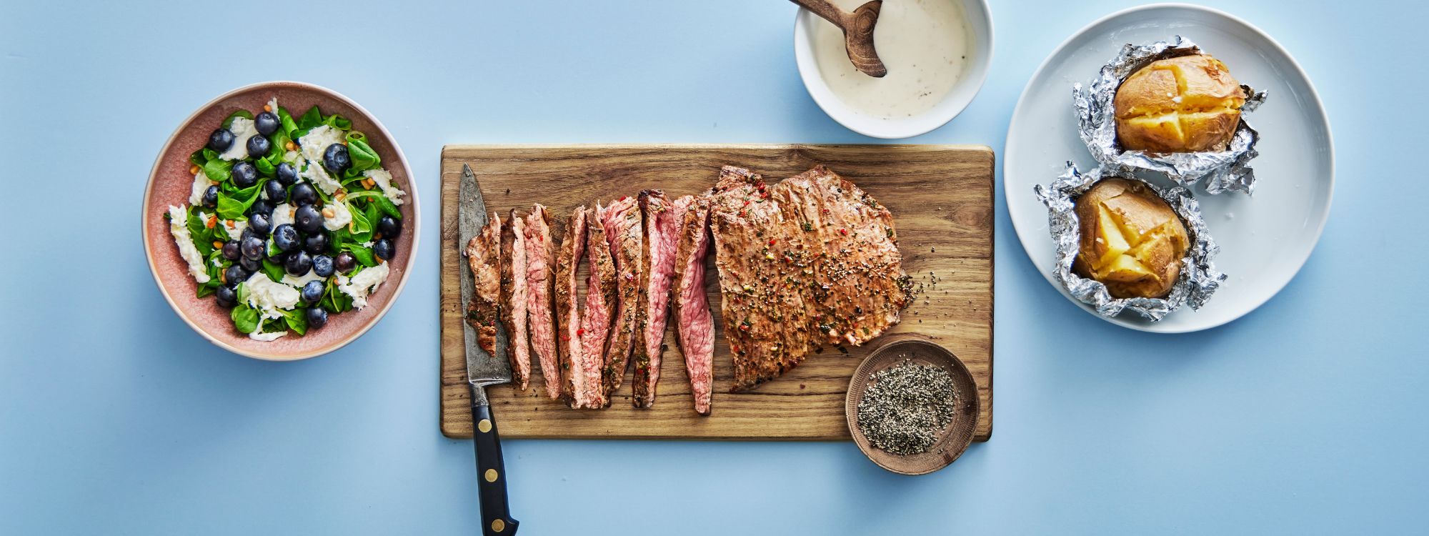 Grillet marineret flanksteak med bagekartofler og tilbehør