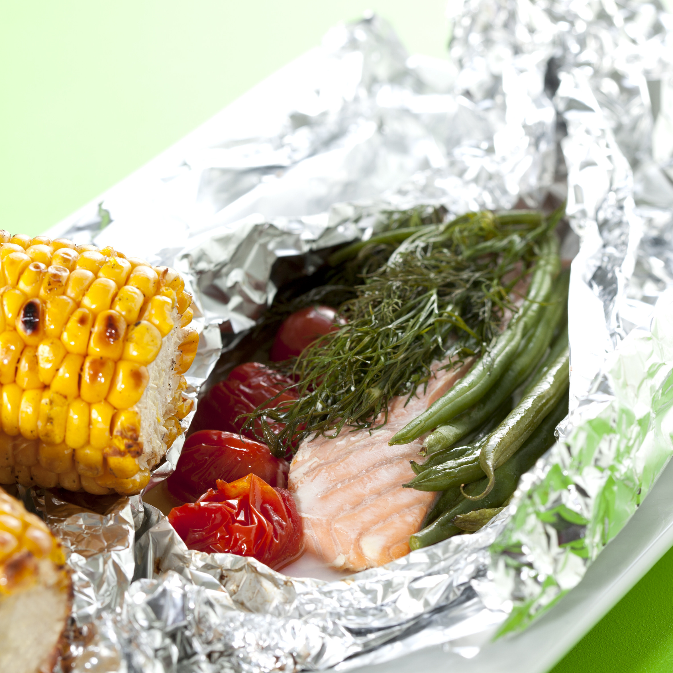 Laks i pakke med tomater, grønne bønner og dild og med grillede majskolber